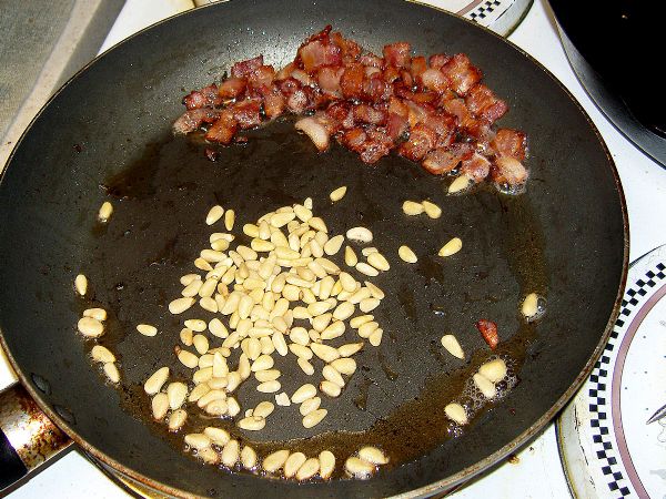 Cook bacon, add pine nuts when bacon is done and toast for a minute or two.
