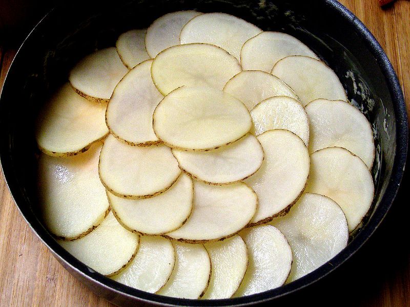 Line the pan with potatoes, layered
