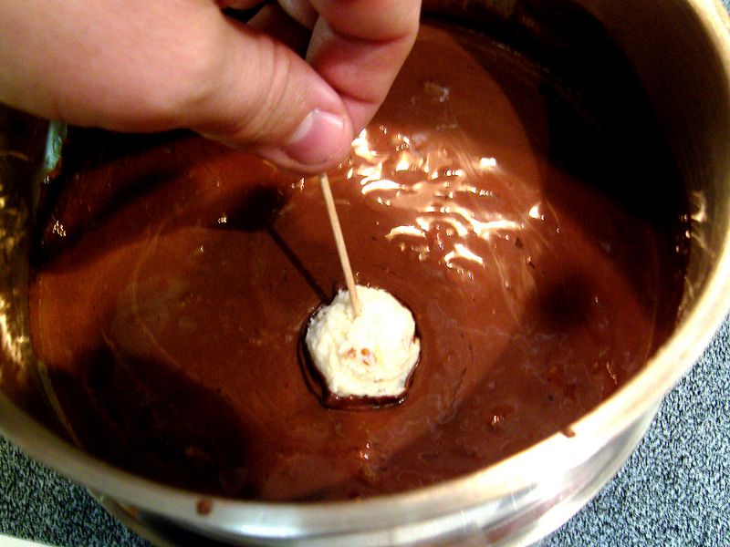 Coat coconut balls in chocolate (one method is with toothpicks)